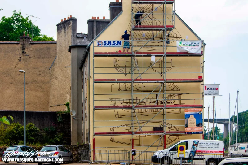 Gwendal Larher, fresquiste et artiste muraliste, devant une fresque monumentale à Morlaix.